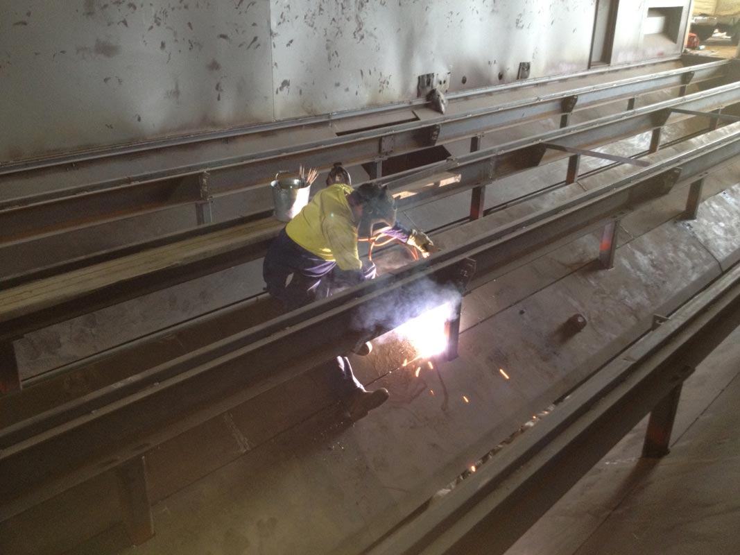 Welding in the sides of a hopper. This is underneath the floor in a sandblasting booth.